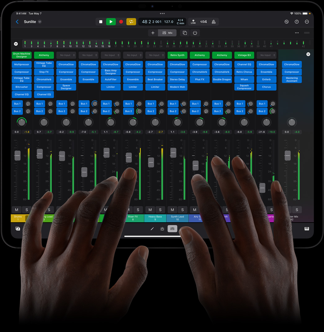 一雙手點觸 iPad Pro 屏幕，正在使用 iPad 版 Logic Pro 的全功能混音控制臺。